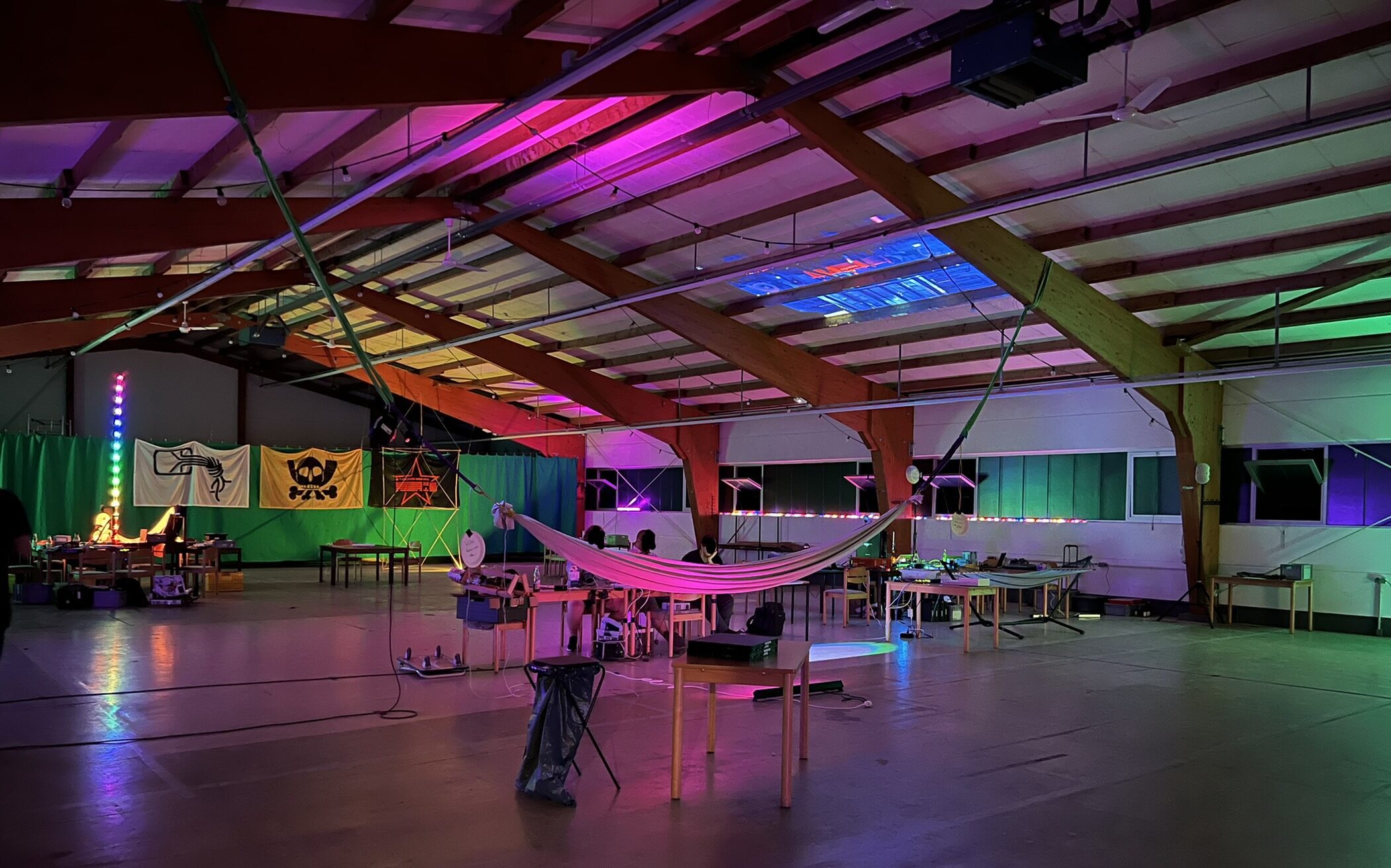 Blick in die mit bunten LED Lichterketten erhellte Schützenhalle mit Hängematte im Vordergrund und div. CCC Flaggen im Hintergrund