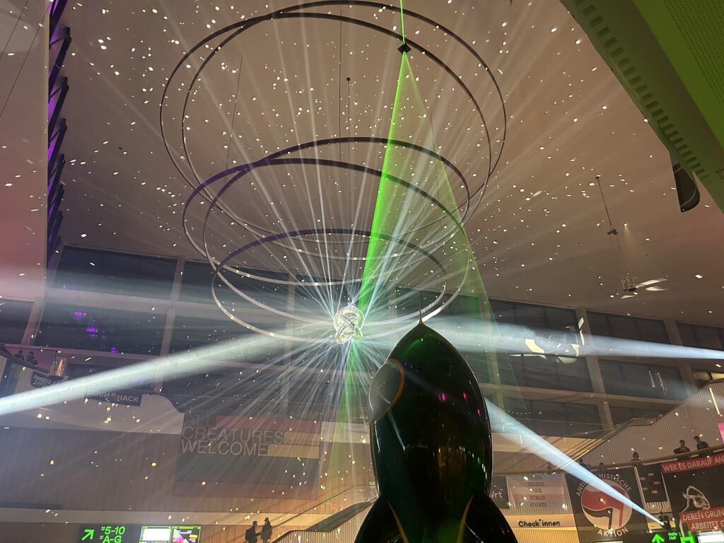 Eingangsbereich des CCH. Unten im Bild ist als Schattenriss die Fairy Dust Rakete zu sehen. Im oberen Teil des Bildes sind vor allem sich kreuzende Lichtstrahlen und Reflexionen zu sehen.